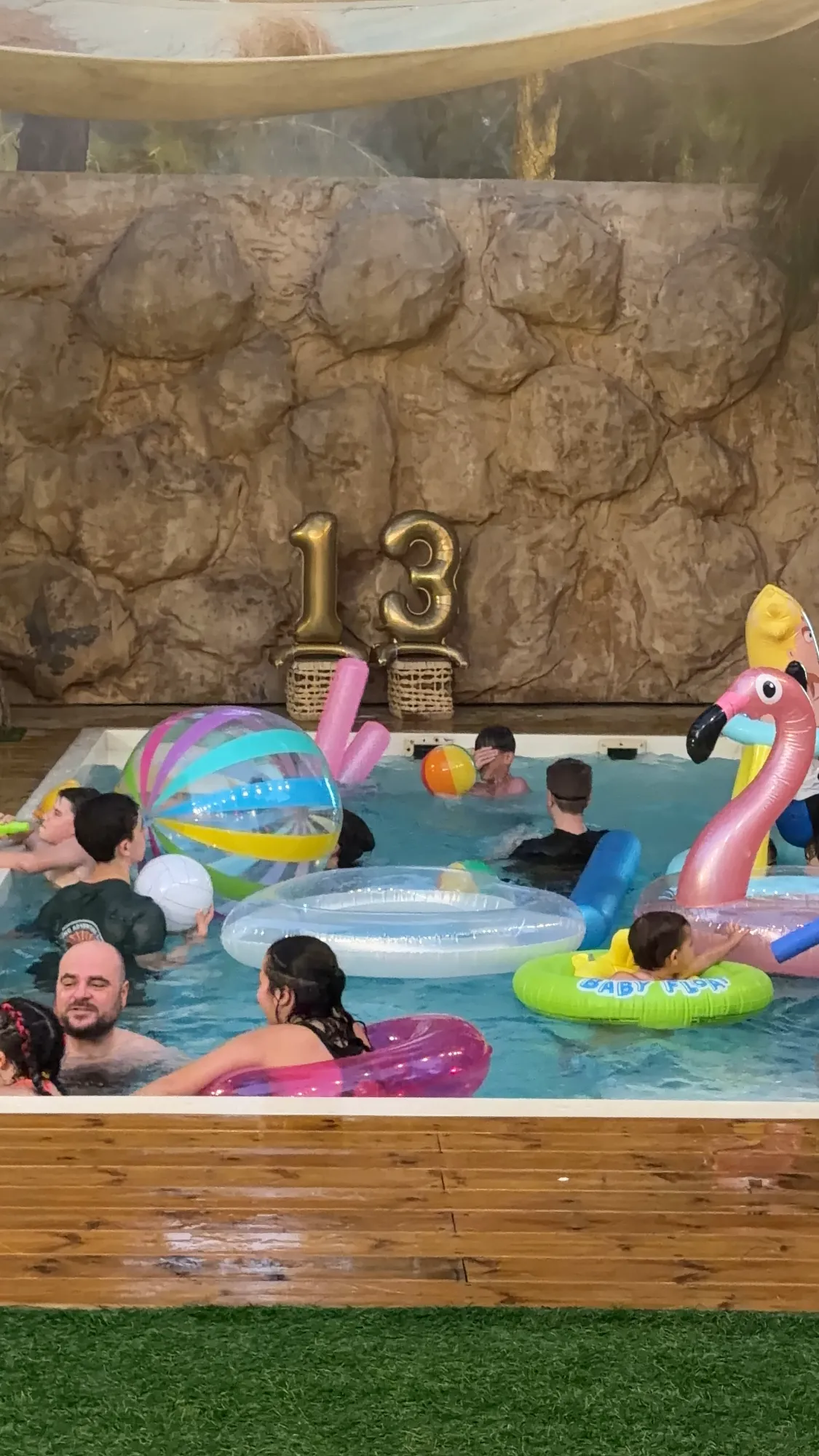 משתתפים ומצופים צבעוניים בבריכה לצד קישוט יום הולדת 13